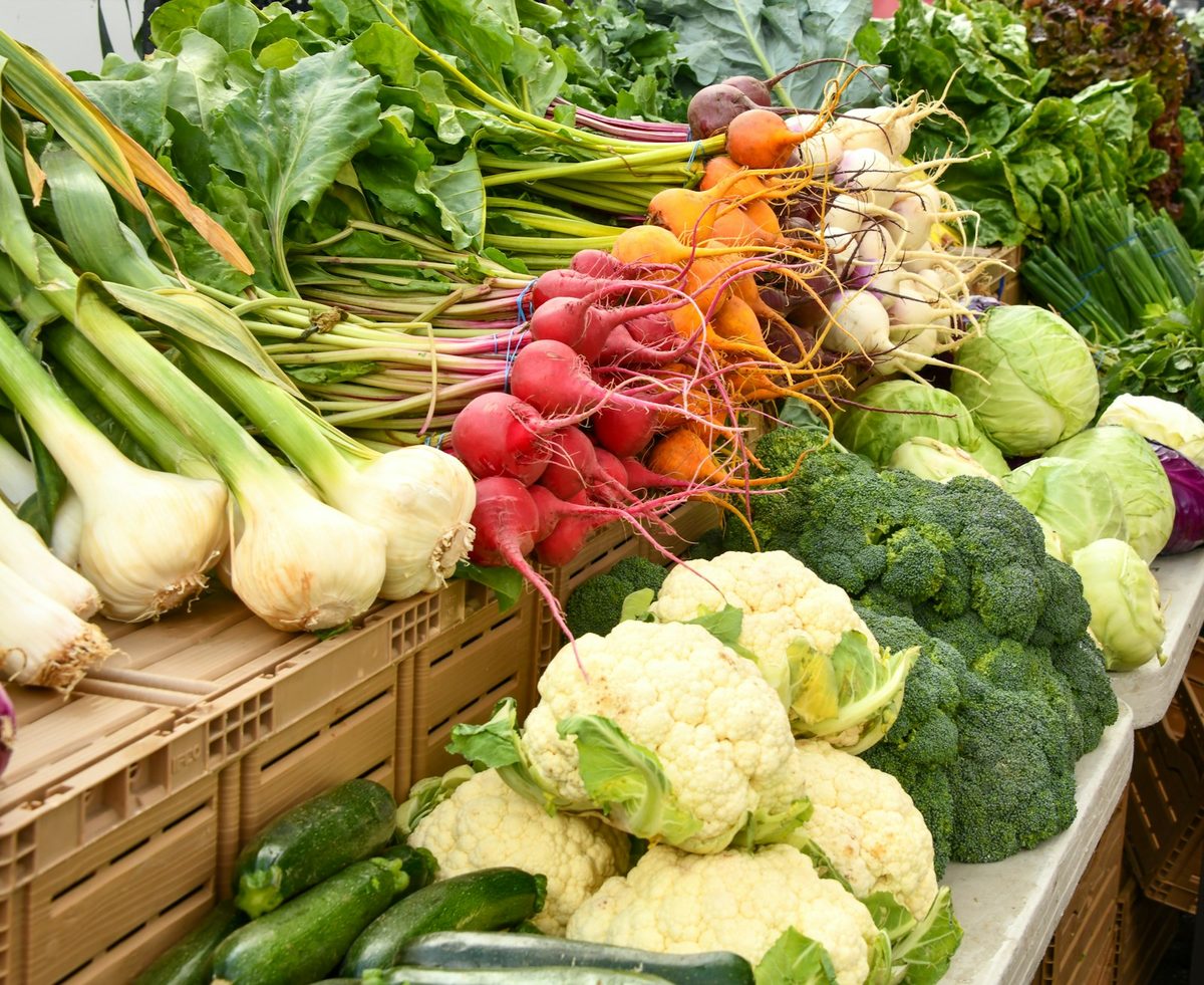 For Dufferin Grove Organic Farmers' Market: Close-up of a market stall: cauliflower, broccoli, radishes and spring onions in crates.