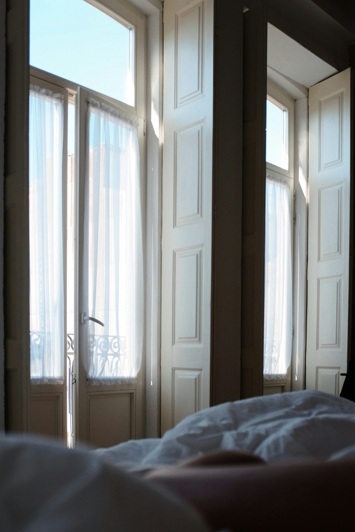 For Four Seasons Hotel Toronto: Bright morning light through two tall French windows onto a white comforter