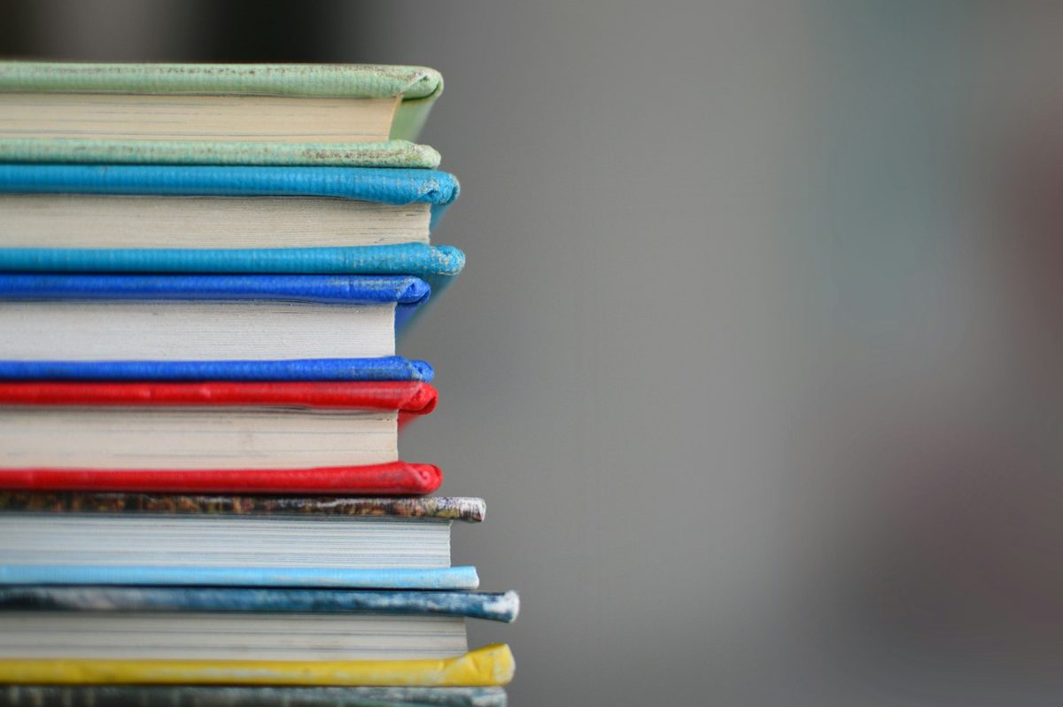 For Mabel's Fables: A stack of cloth-bound books in bright blues, reds and greens, soft background.