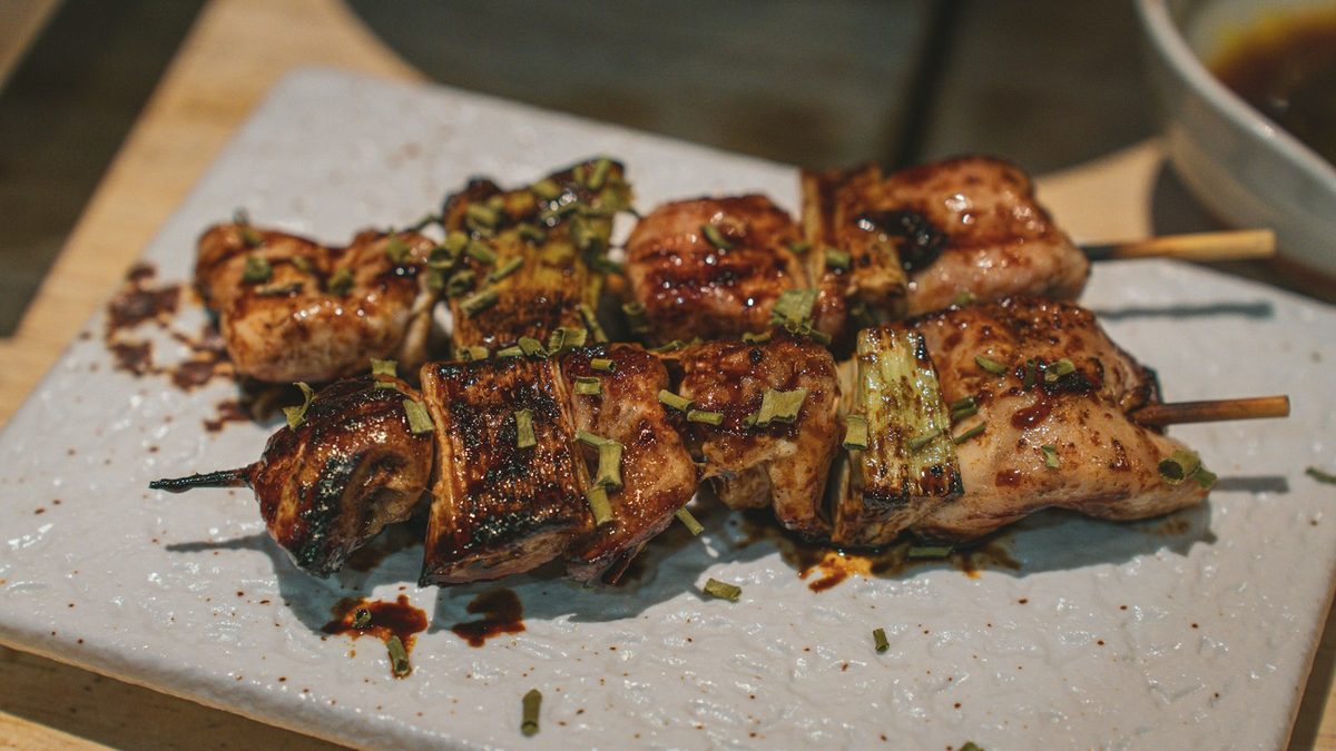 For Mhel: Two glazed chicken yakitori skewers on a stone-grey plate, close up