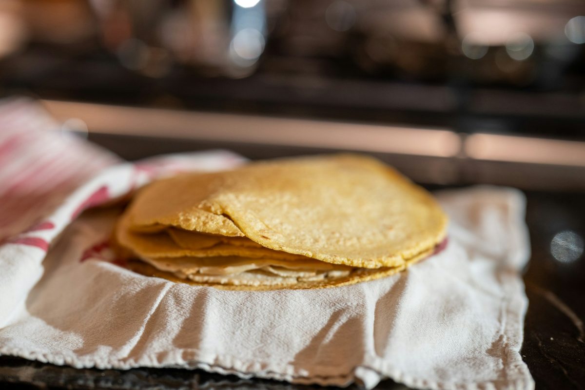 For Quetzal: A stack of fresh corn tortillas on a cloth in warm, low light