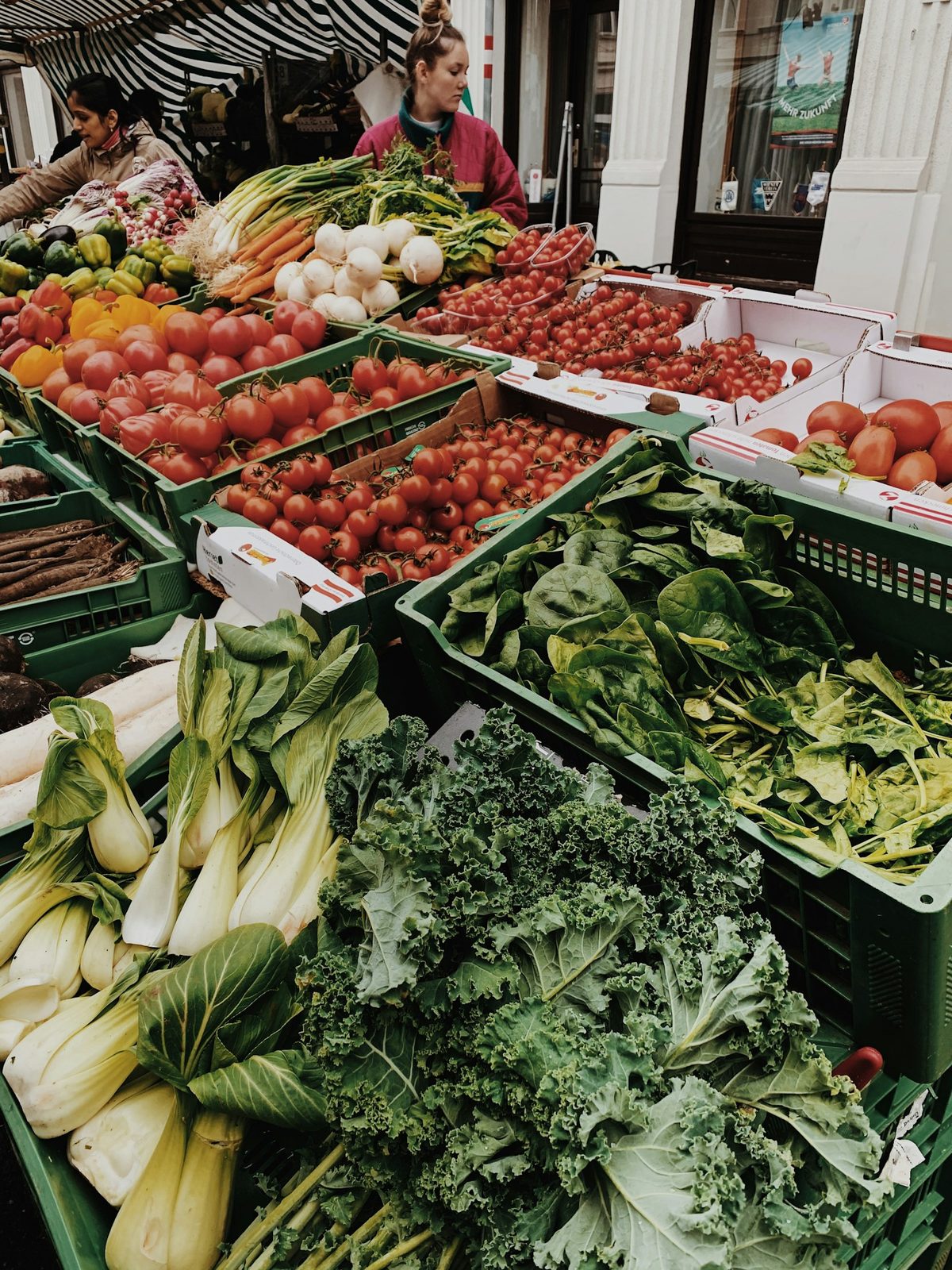 For Trinity Bellwoods Farmers' Market: Crates of leafy greens and vegetables at an outdoor market stall.