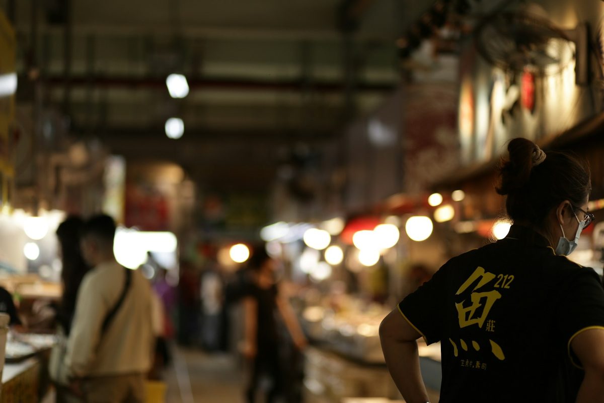 For Underground Night Market: A crowded night market lit by warm string lights, shoppers in soft focus.