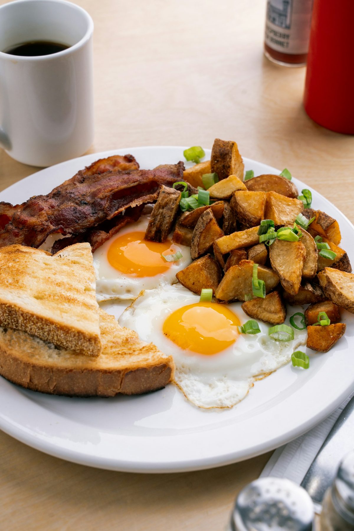 For White Lily Diner: A diner plate of sunny-side eggs, toast, bacon and home fries with a mug of black coffee